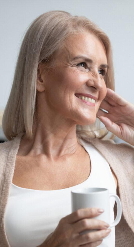 Woman smiling with a cup of coffee after cognitive performance treatment